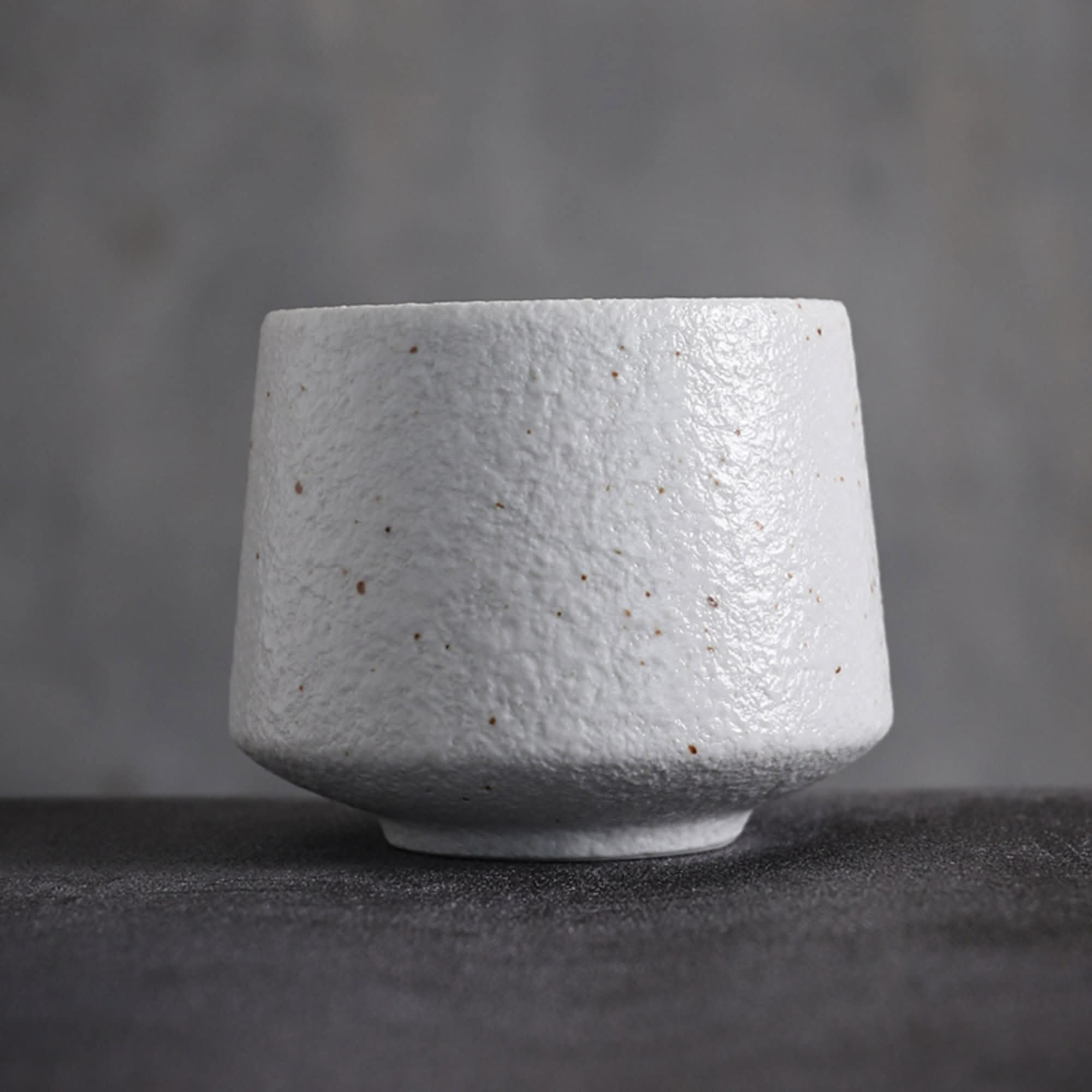 Textured gray Japanese tea cup with speckled detail, minimalist home decor.